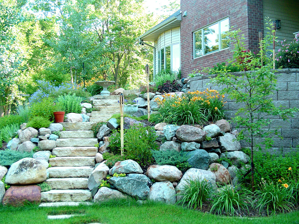Cette photo montre un jardin chic de taille moyenne avec une pente, une colline ou un talus, des pavés en pierre naturelle et pierres et graviers.