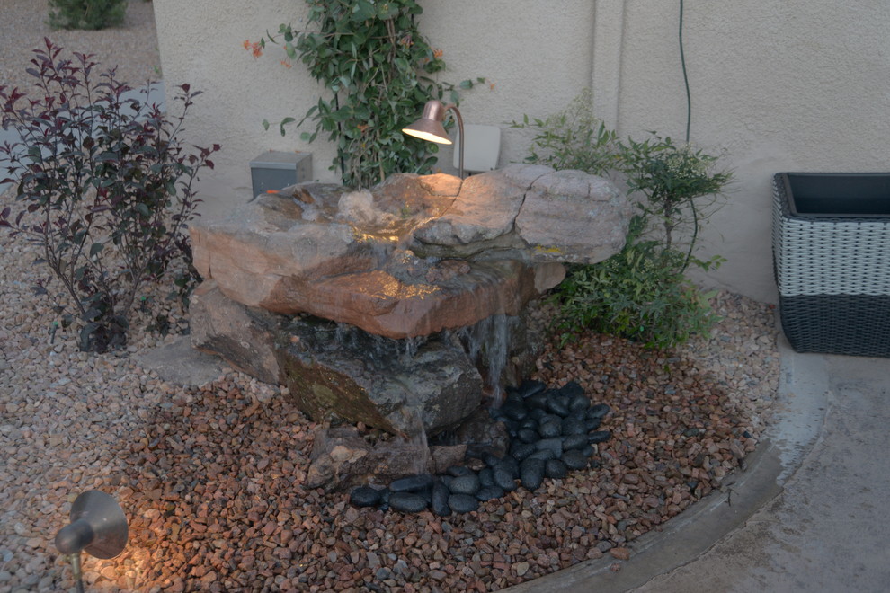 Geometrischer Mediterraner Garten hinter dem Haus mit Feuerstelle, direkter Sonneneinstrahlung und Natursteinplatten in Albuquerque