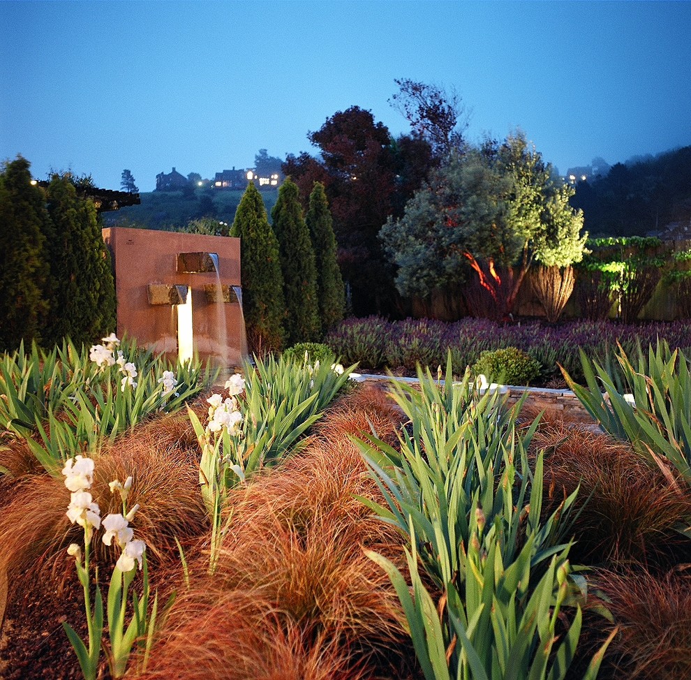 Imagen de jardín mediterráneo grande en patio trasero con fuente, jardín francés, exposición parcial al sol y adoquines de hormigón