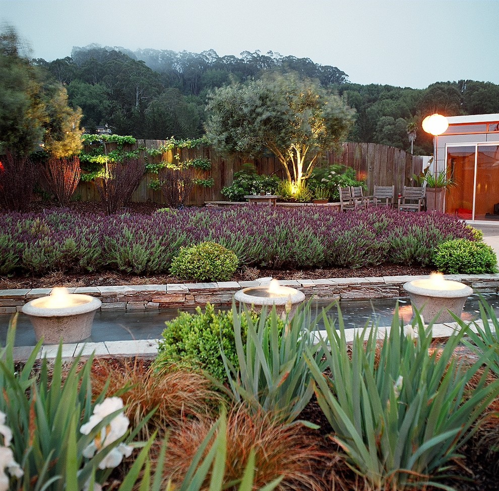Immagine di un grande giardino formale mediterraneo esposto a mezz'ombra dietro casa con fontane e ghiaia