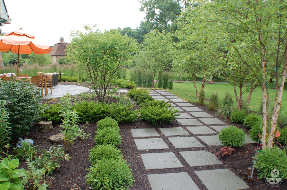 Пример оригинального дизайна: большой солнечный, весенний регулярный сад на заднем дворе в современном стиле с садовой дорожкой или калиткой, хорошей освещенностью и покрытием из каменной брусчатки