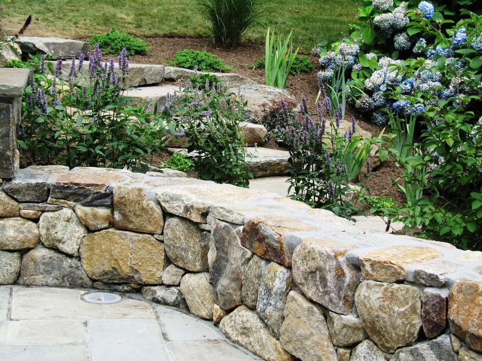 Medium sized classic back partial sun garden for summer in New York with a retaining wall and natural stone paving.