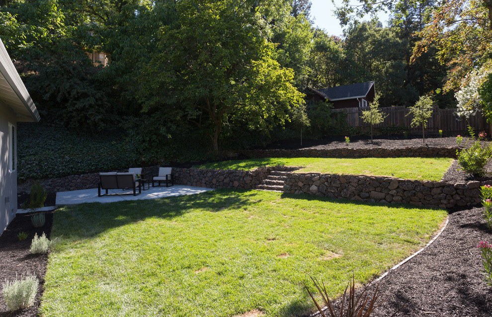 На фото: регулярный сад среднего размера на заднем дворе в стиле кантри с подпорной стенкой, полуденной тенью и мульчированием с