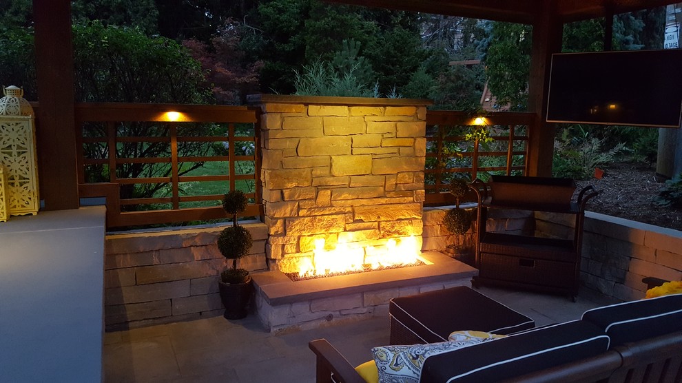 Example of a mid-sized trendy backyard stone patio design in Milwaukee with a fire pit