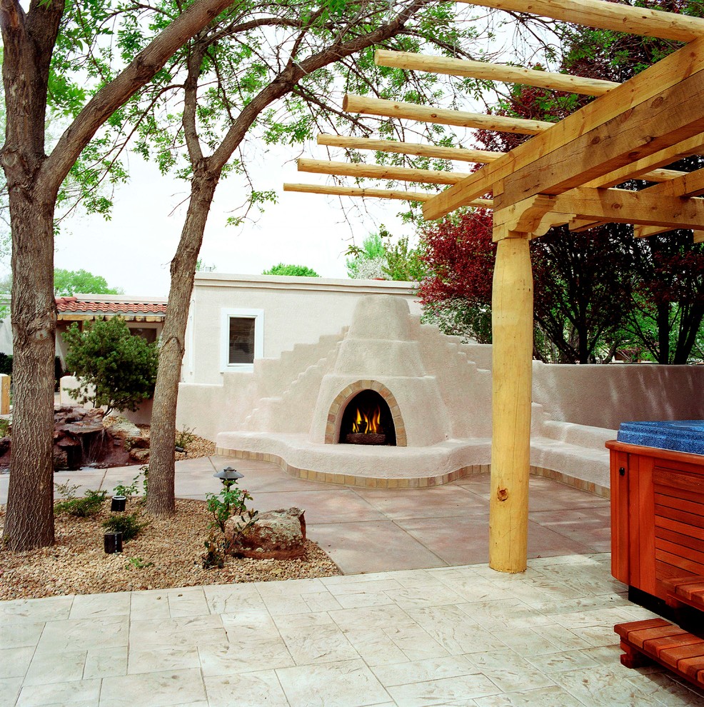 Cette photo montre une grande terrasse arrière sud-ouest américain avec un foyer extérieur et des pavés en béton.