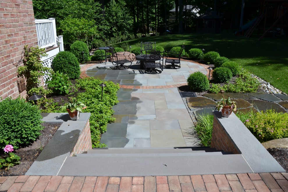 Modelo de jardín clásico de tamaño medio en verano en patio trasero con exposición parcial al sol y adoquines de piedra natural