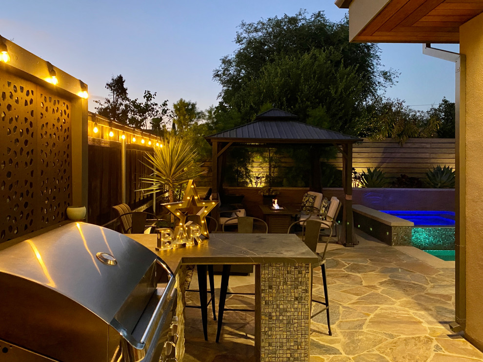 Photo of a medium sized contemporary back xeriscape full sun garden for summer in San Diego with a fire feature, natural stone paving and a wood fence.