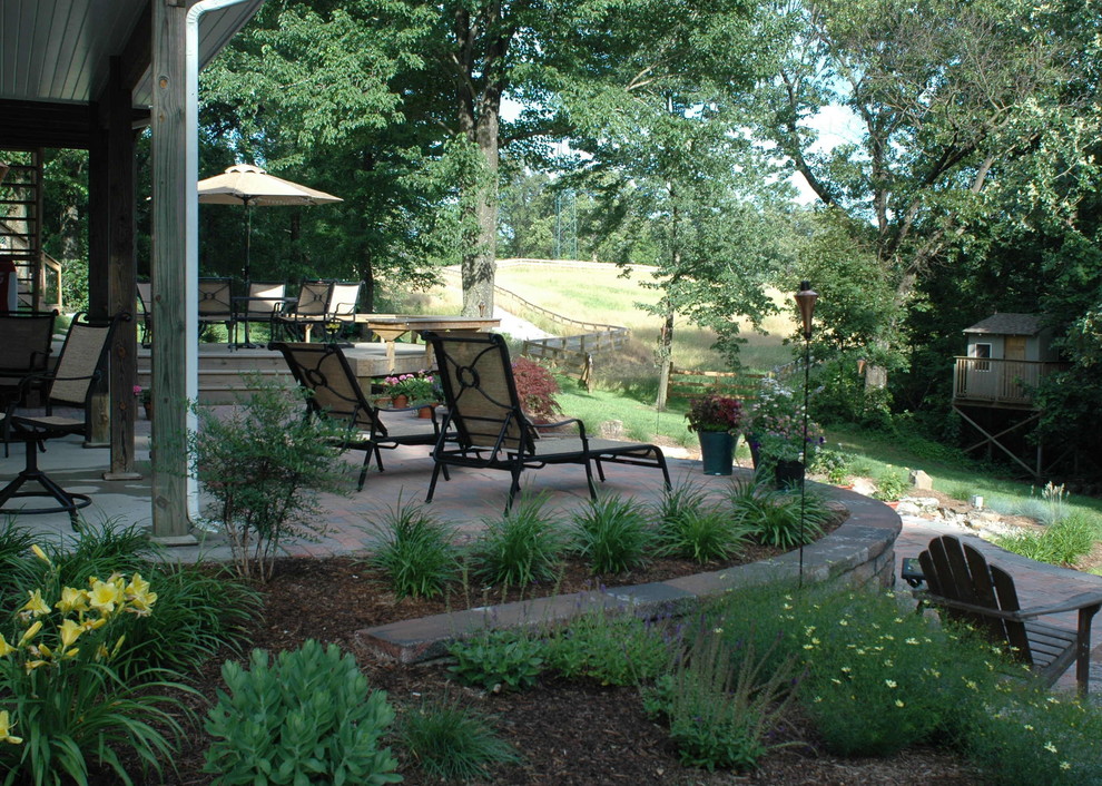 Exempel på en mellanstor klassisk trädgård, med en damm och marksten i tegel