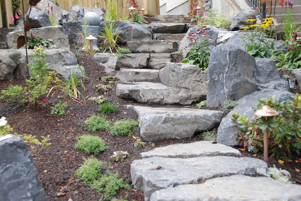 Modelo de jardín tradicional renovado de tamaño medio en patio delantero con muro de contención y adoquines de piedra natural