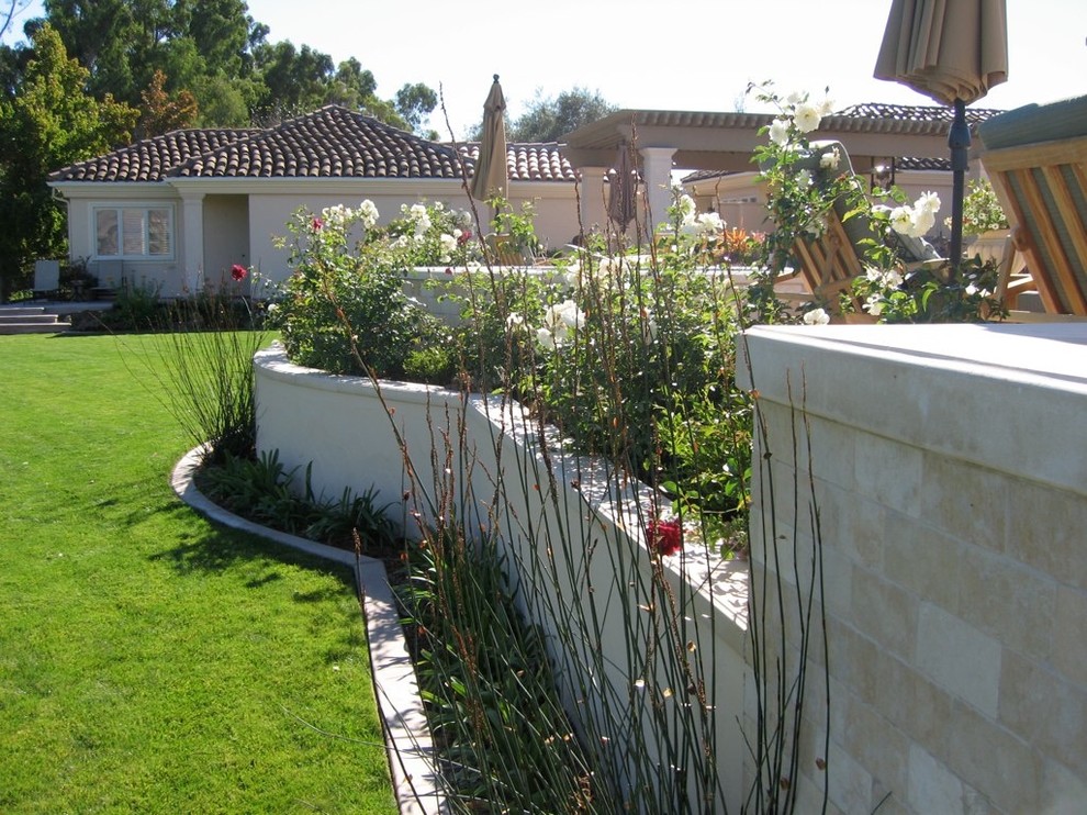 Immagine di un ampio giardino mediterraneo esposto in pieno sole dietro casa in estate con pavimentazioni in cemento