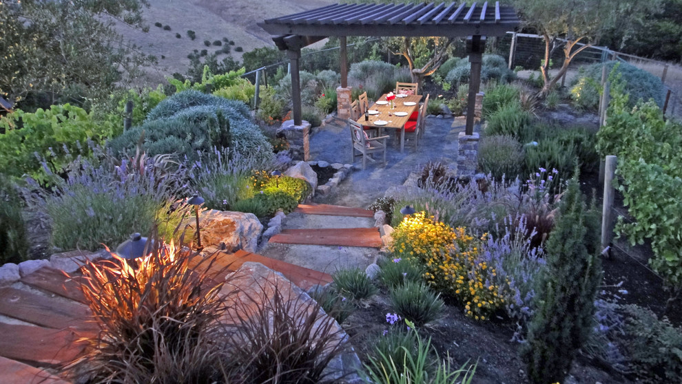 Ejemplo de jardín tradicional de tamaño medio en primavera en patio trasero con muro de contención, exposición total al sol y adoquines de piedra natural