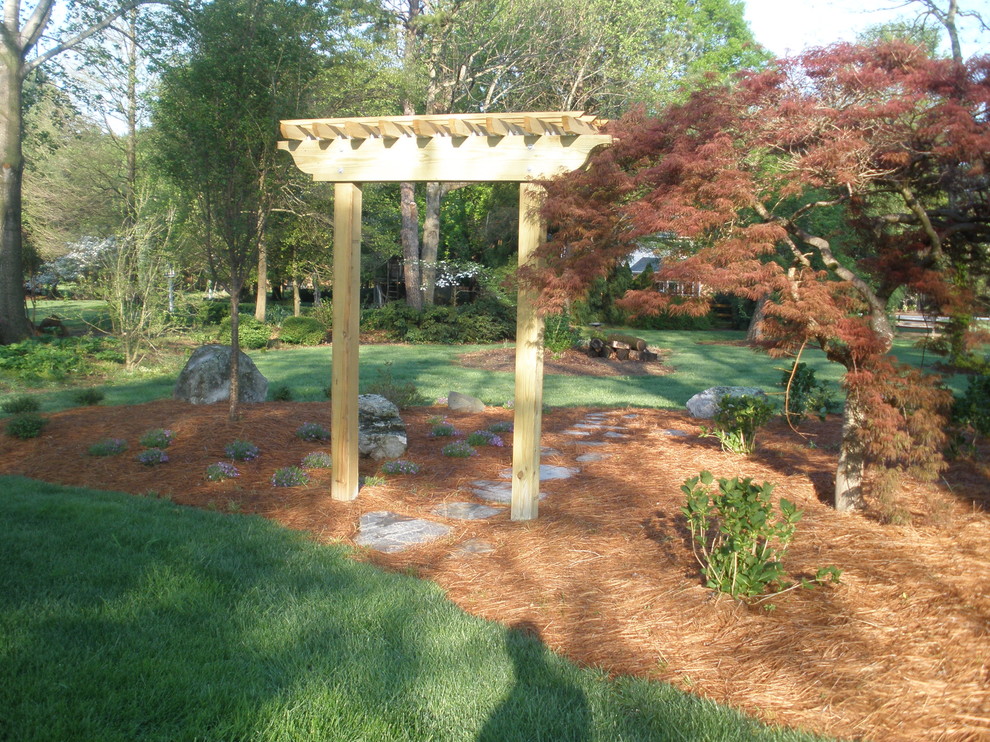 Cette image montre un aménagement d'entrée ou allée de jardin latéral traditionnel avec une exposition partiellement ombragée et des pavés en pierre naturelle.