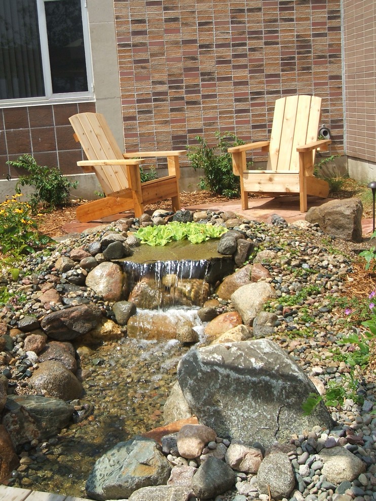 Cette image montre un petit jardin à la française arrière traditionnel avec un bassin, une exposition ensoleillée et des pavés en pierre naturelle.