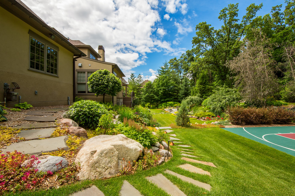 This is an example of a large classic back partial sun garden for summer in Minneapolis with an outdoor sport court, a garden path and natural stone paving.