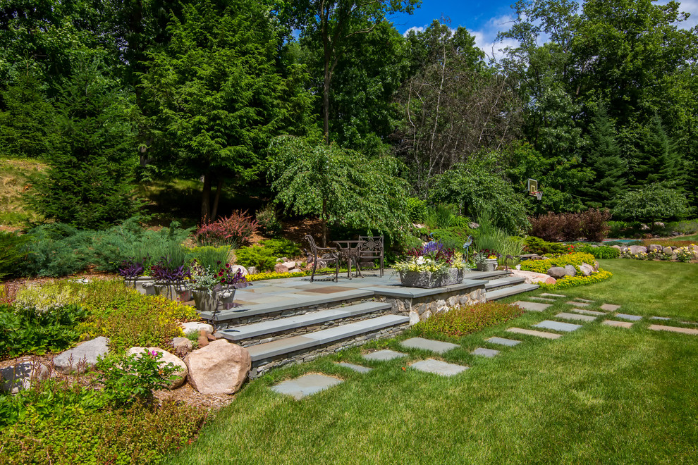 Immagine di un grande giardino formale tradizionale esposto a mezz'ombra dietro casa in estate con pavimentazioni in pietra naturale e un ingresso o sentiero