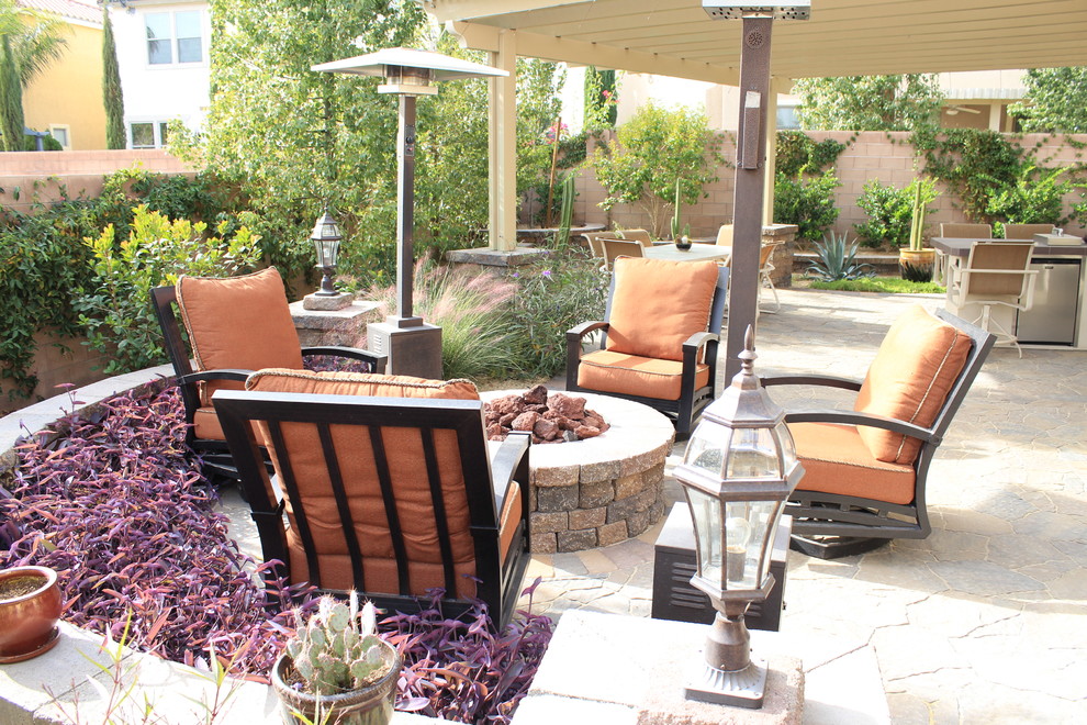 This is an example of a medium sized classic back patio in Las Vegas with a fire feature and natural stone paving.