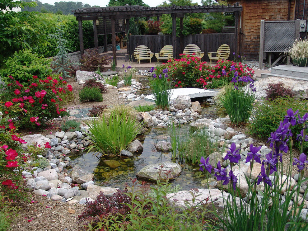 This is an example of a mid-sized traditional full sun backyard stone landscaping in Other for spring.