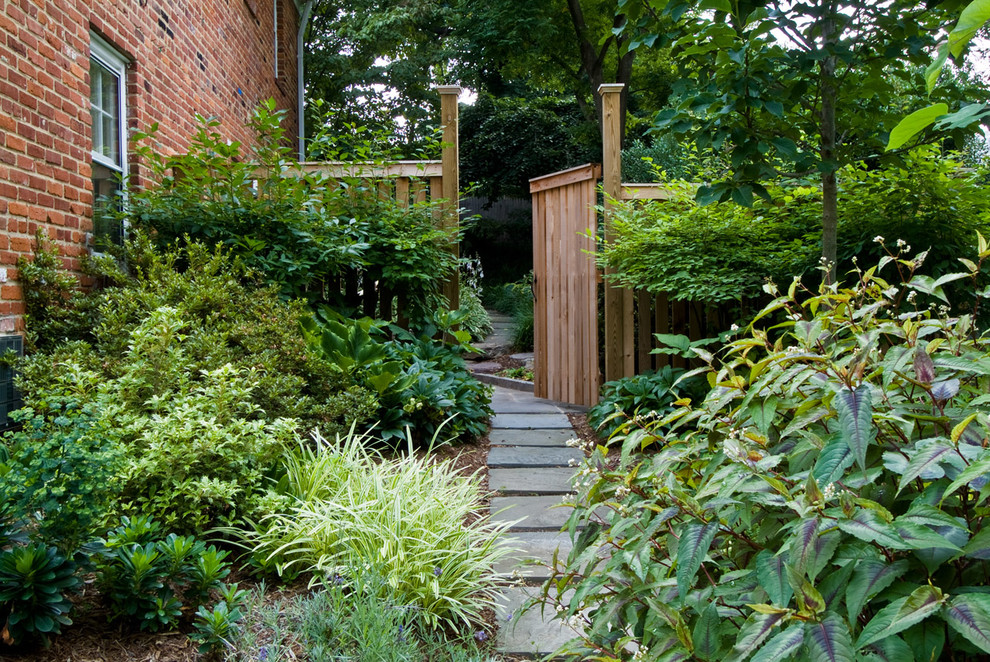 Réalisation d'un grand jardin arrière tradition l'été avec une exposition partiellement ombragée et des pavés en pierre naturelle.