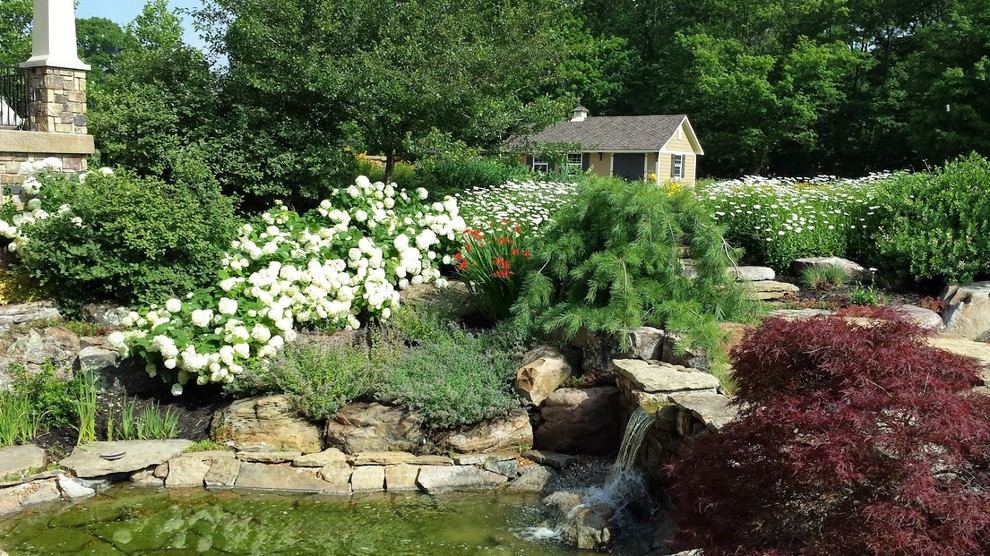 Großer Klassischer Garten hinter dem Haus mit Wasserspiel, direkter Sonneneinstrahlung und Natursteinplatten in Indianapolis