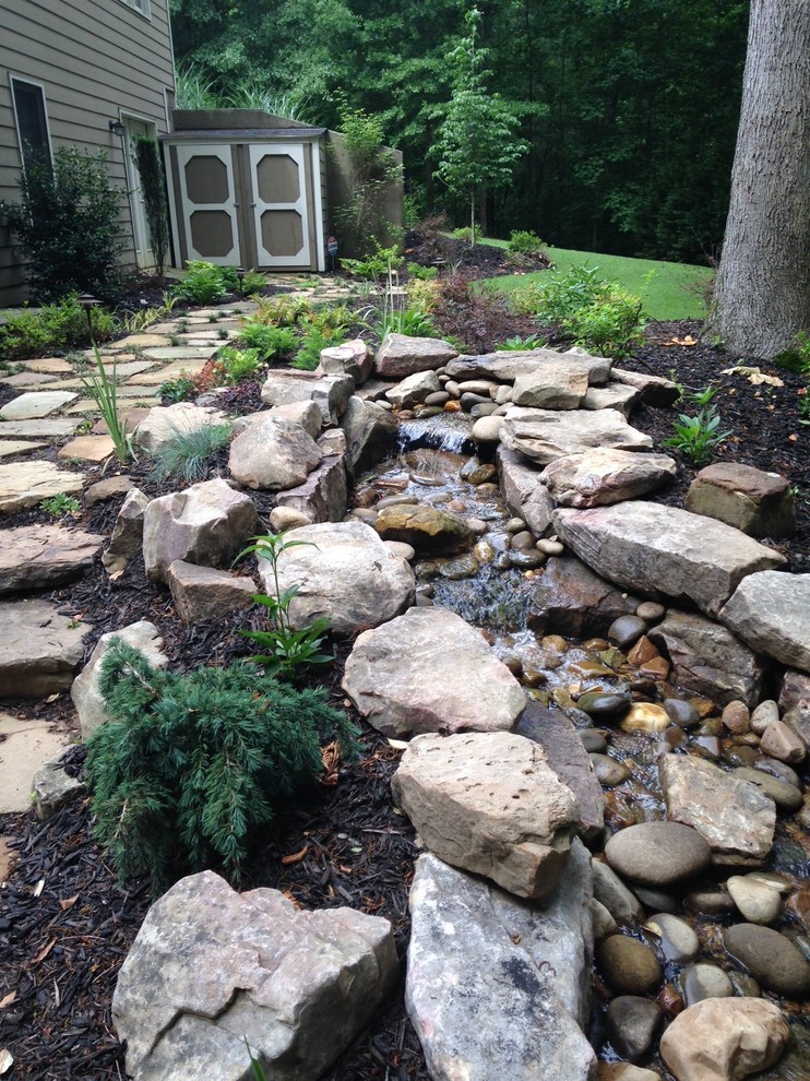Inspiration pour un grand jardin latéral traditionnel au printemps avec une exposition ensoleillée et des pavés en pierre naturelle.