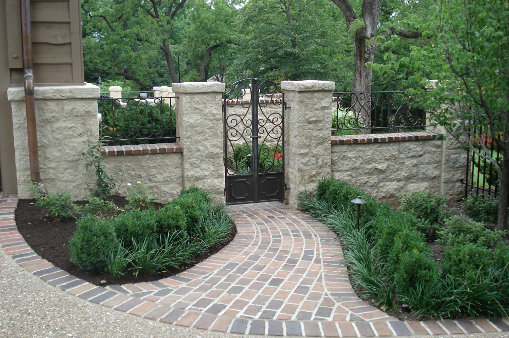 Esempio di un giardino classico esposto in pieno sole nel cortile laterale con cancello e pavimentazioni in mattoni
