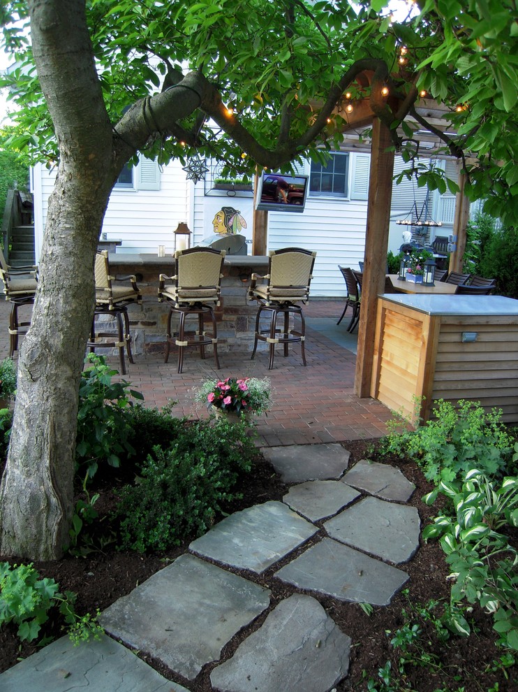 Foto de jardín clásico renovado de tamaño medio en patio trasero con brasero, exposición reducida al sol y adoquines de ladrillo