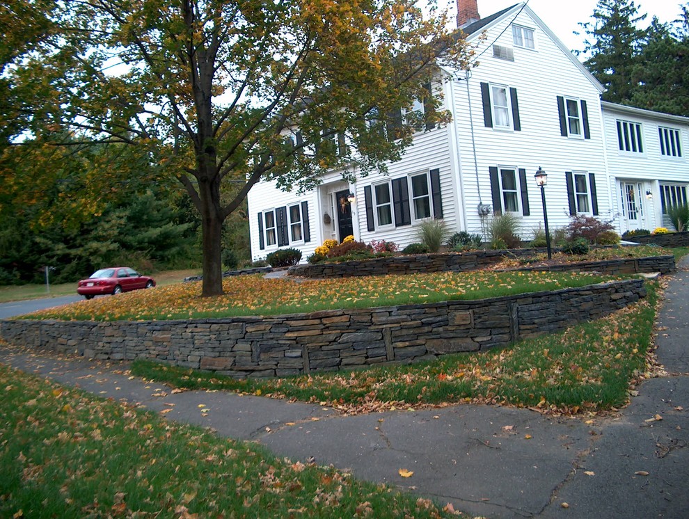 Foto de acceso privado tradicional de tamaño medio en patio delantero con muro de contención y adoquines de piedra natural