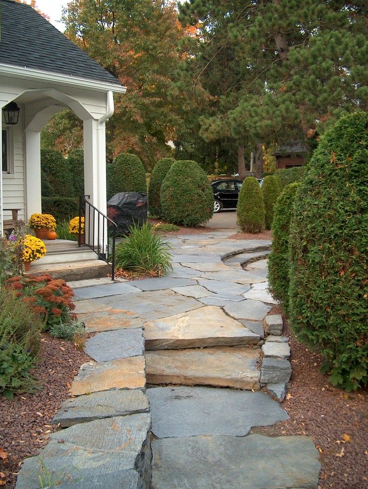 Imagen de acceso privado tradicional renovado de tamaño medio en patio delantero con muro de contención y adoquines de piedra natural