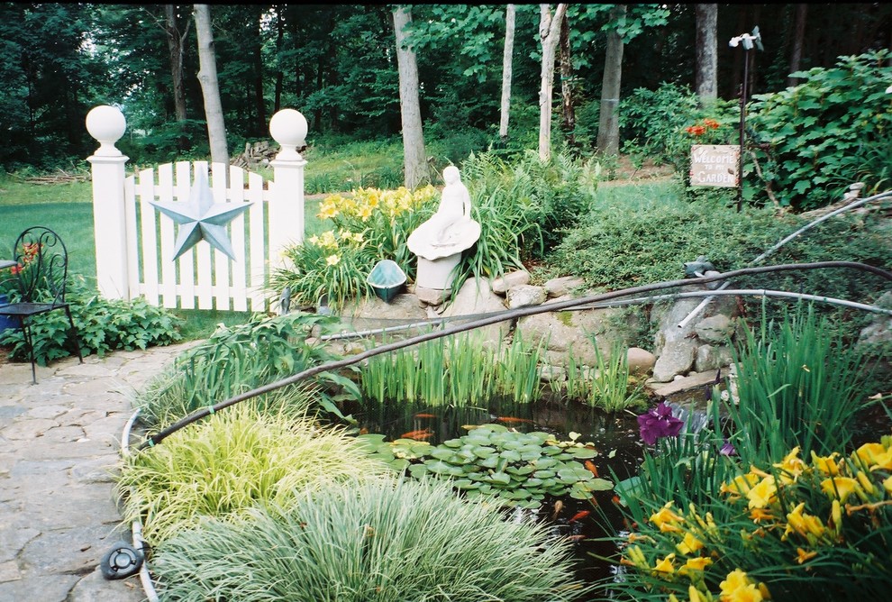Modelo de jardín campestre de tamaño medio en verano en patio trasero con exposición parcial al sol, adoquines de piedra natural, jardín francés y estanque