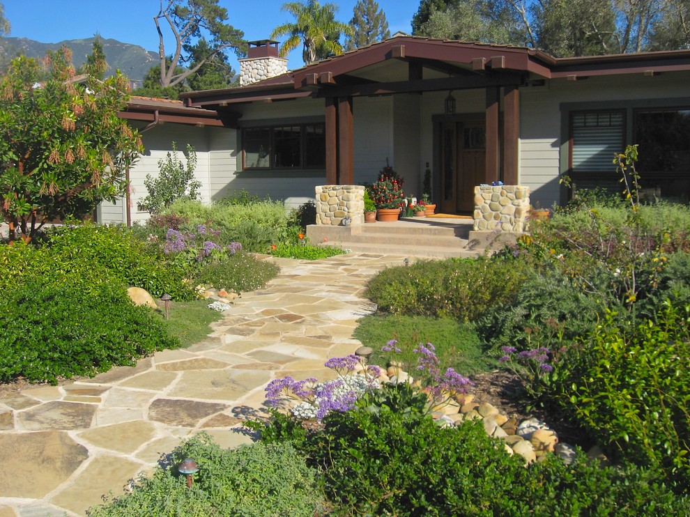 This is an example of a large traditional front full sun garden in Orange County with natural stone paving.