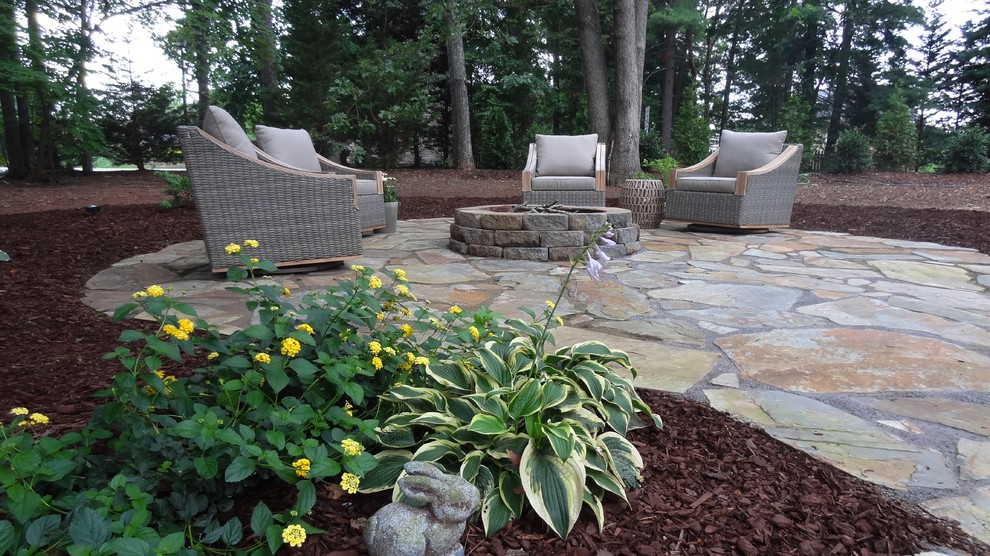 Photo of a mid-sized traditional partial sun backyard stone landscaping in Other with a fire pit for fall.