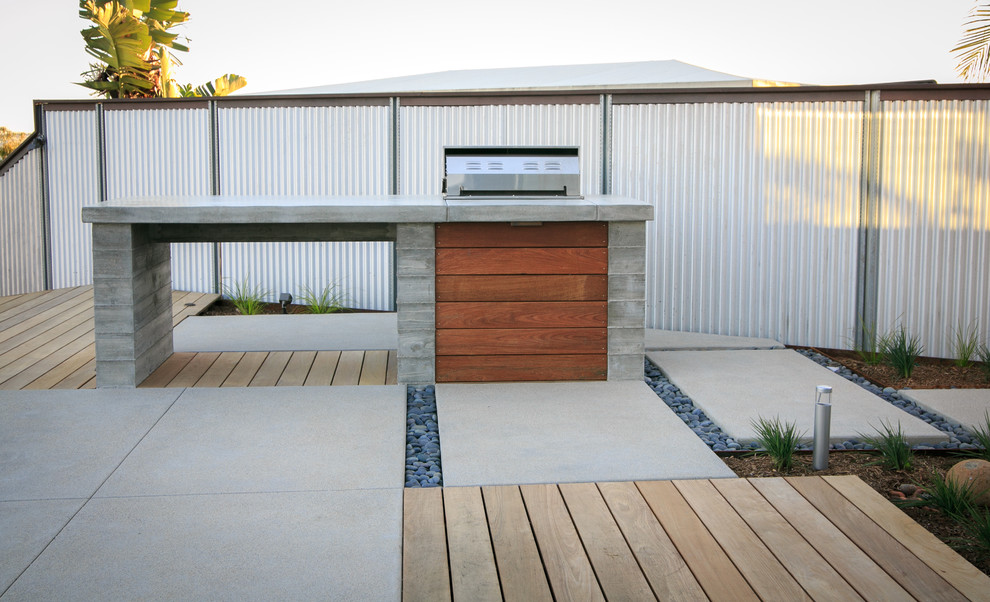 Diseño de jardín minimalista en patio trasero con exposición total al sol y adoquines de hormigón
