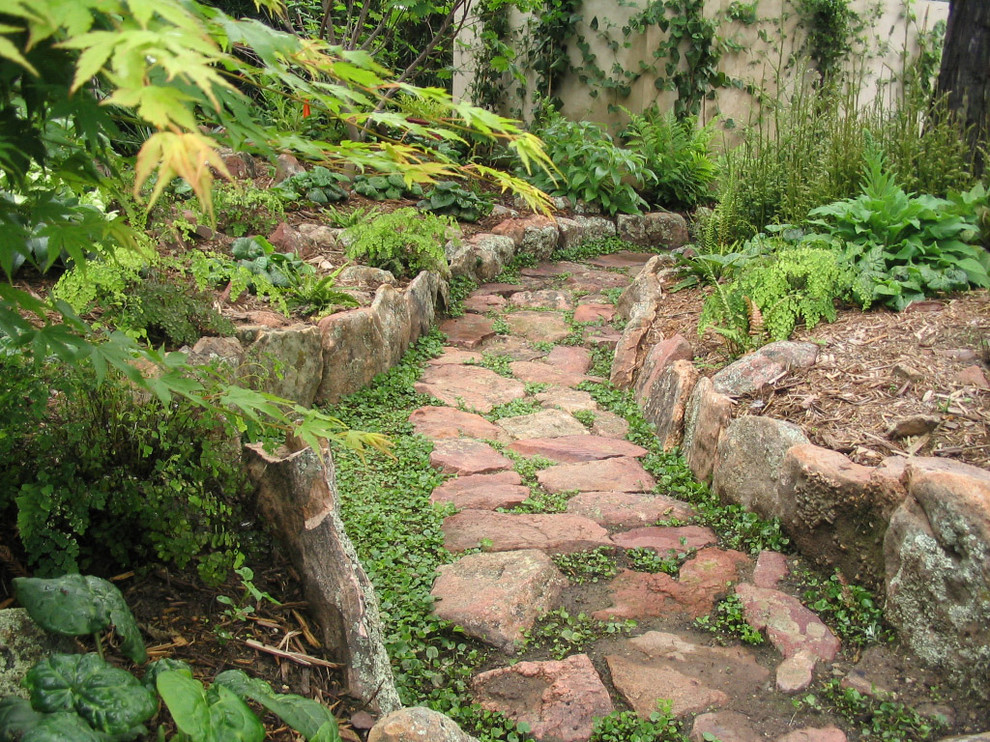 Aménagement d'un jardin arrière éclectique avec une exposition ombragée et des pavés en pierre naturelle.
