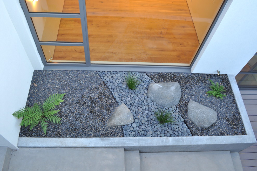 Foto de jardín minimalista en patio lateral con muro de contención, exposición reducida al sol y gravilla