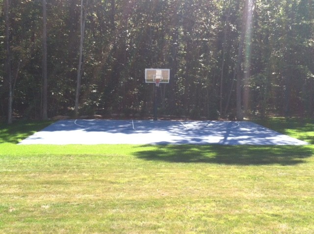 Ejemplo de pista deportiva descubierta tradicional grande en patio trasero con exposición parcial al sol