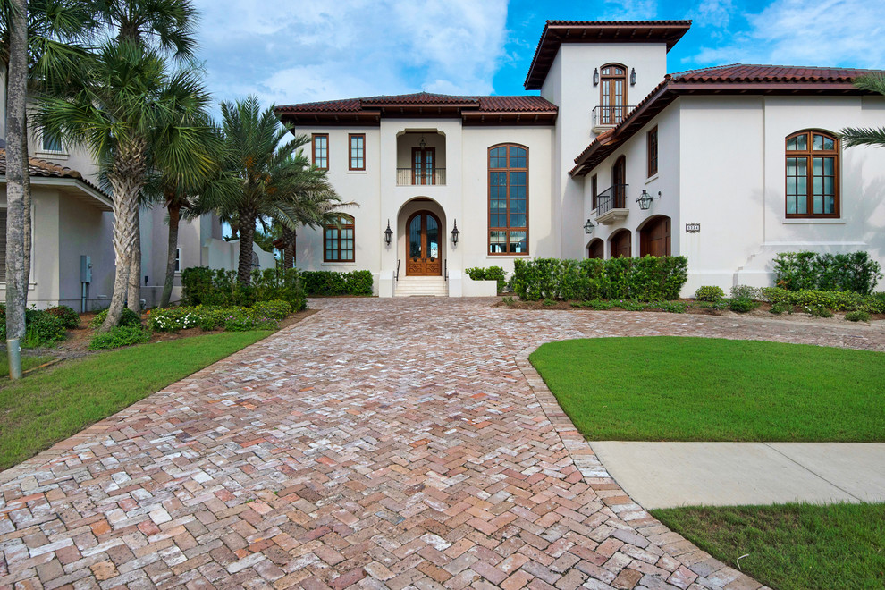 Inspiration for a large mediterranean front driveway partial sun garden in Miami with a water feature and brick paving.