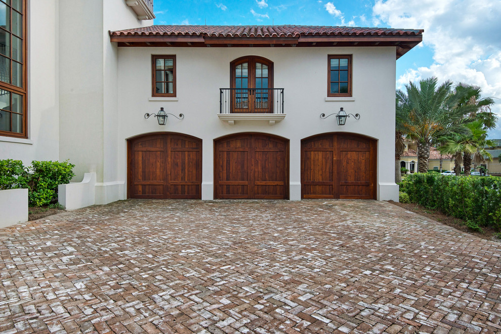 Design ideas for a large mediterranean front driveway partial sun garden for summer in Miami with a water feature and brick paving.
