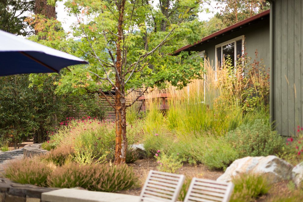 На фото: большой солнечный засухоустойчивый сад на заднем дворе в стиле модернизм с подпорной стенкой, хорошей освещенностью и покрытием из каменной брусчатки с
