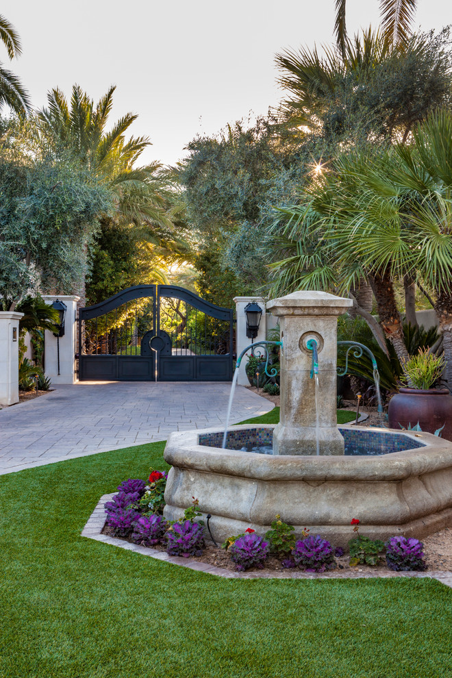 Diseño de acceso privado mediterráneo en patio delantero con fuente y adoquines de hormigón