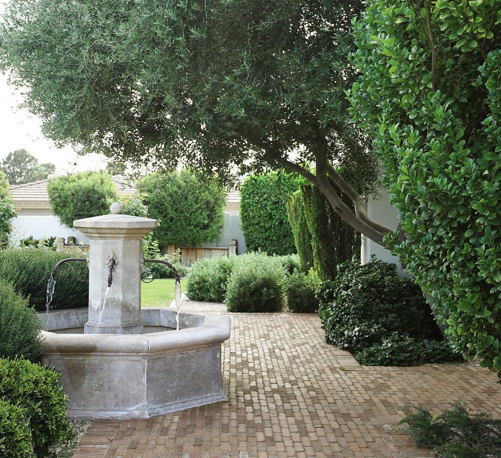 Cette image montre un très grand jardin à la française arrière traditionnel avec un point d'eau et des pavés en brique.