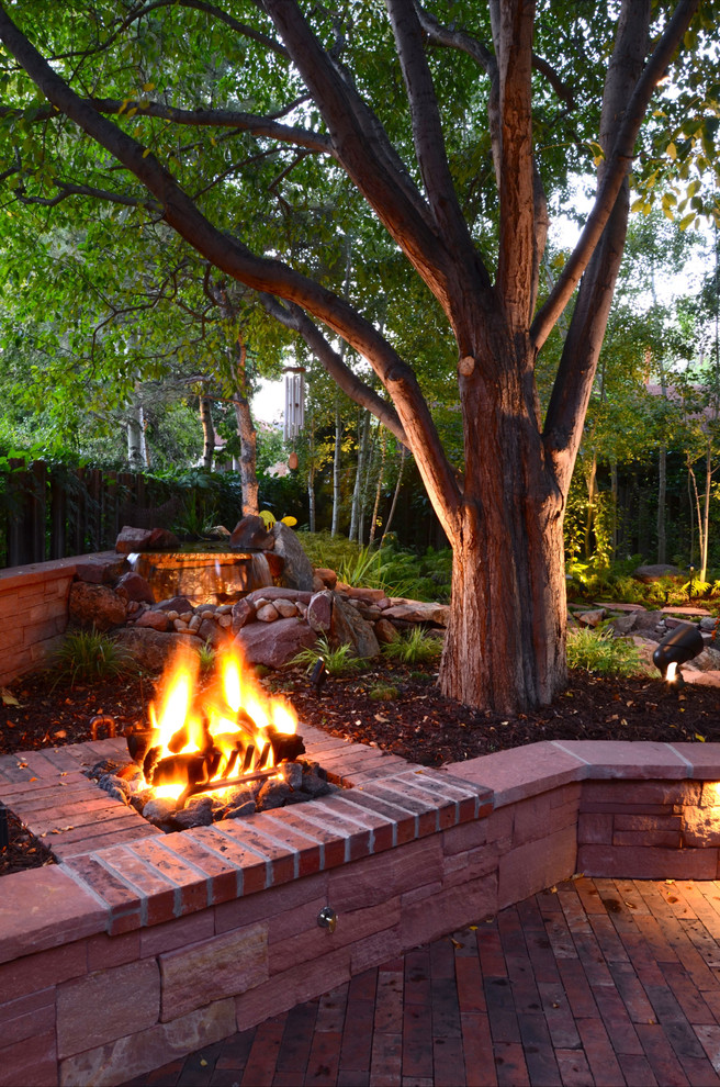Inspiration for a traditional backyard brick landscaping in Denver with a fire pit.
