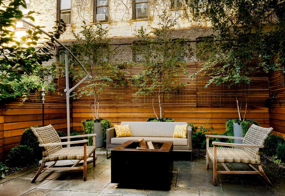 Modelo de patio moderno en patio trasero con brasero y adoquines de piedra natural