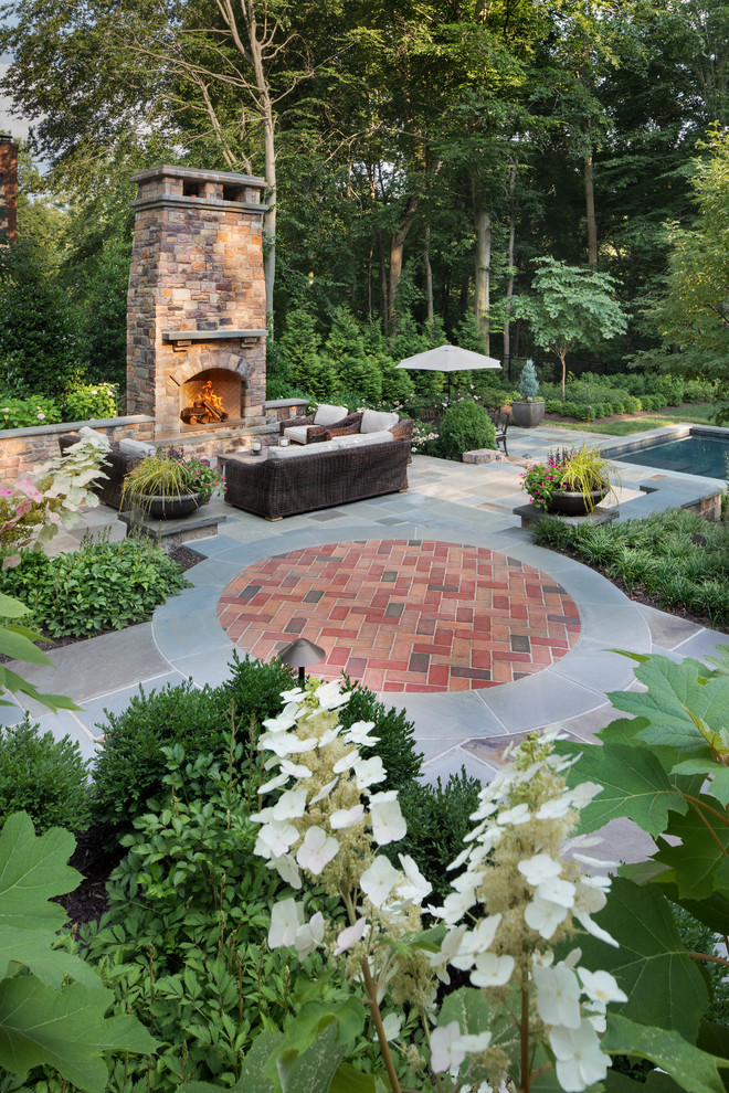 Ejemplo de jardín clásico grande en patio trasero con brasero, exposición parcial al sol y adoquines de piedra natural