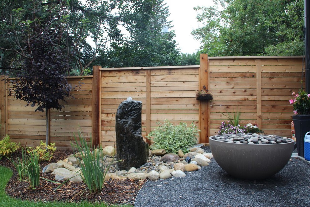 Cette image montre un jardin arrière design de taille moyenne avec un point d'eau, une exposition ensoleillée et du gravier.