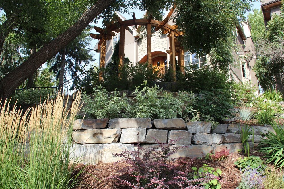 This is an example of a mid-sized rustic partial sun backyard stone landscaping in Calgary.