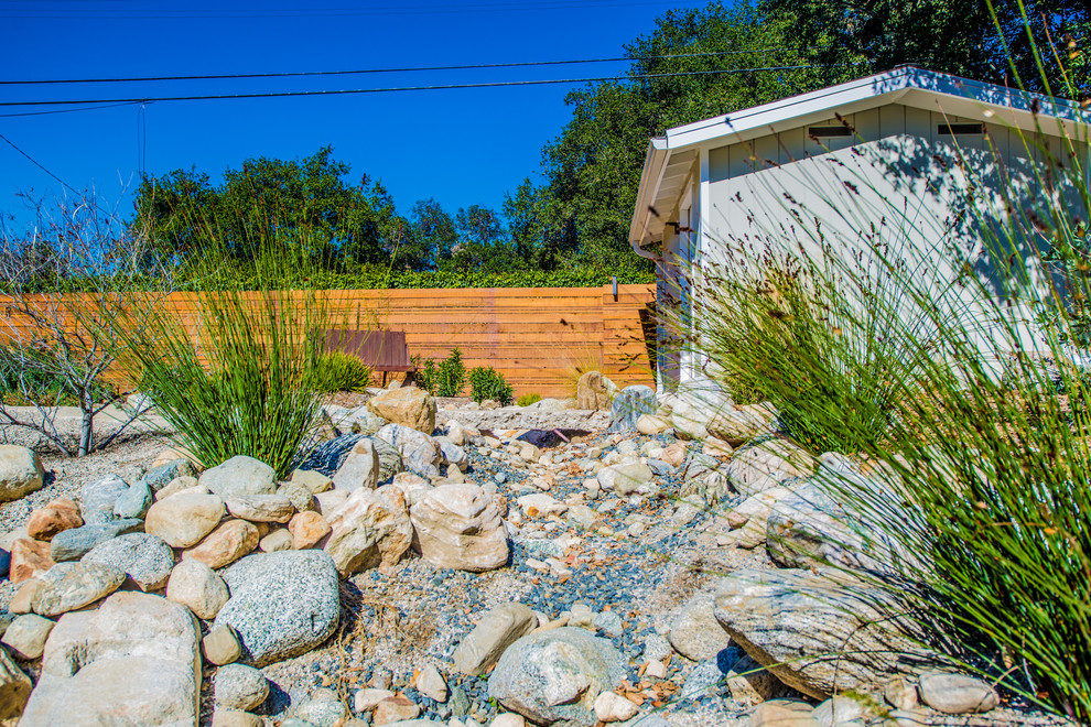Imagen de jardín de secano tradicional de tamaño medio en verano en patio delantero con exposición total al sol, adoquines de piedra natural y muro de contención