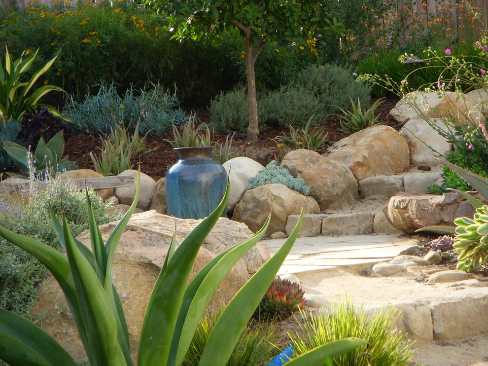 На фото: участок и сад на склоне в средиземноморском стиле с покрытием из каменной брусчатки и камнем в ландшафтном дизайне с