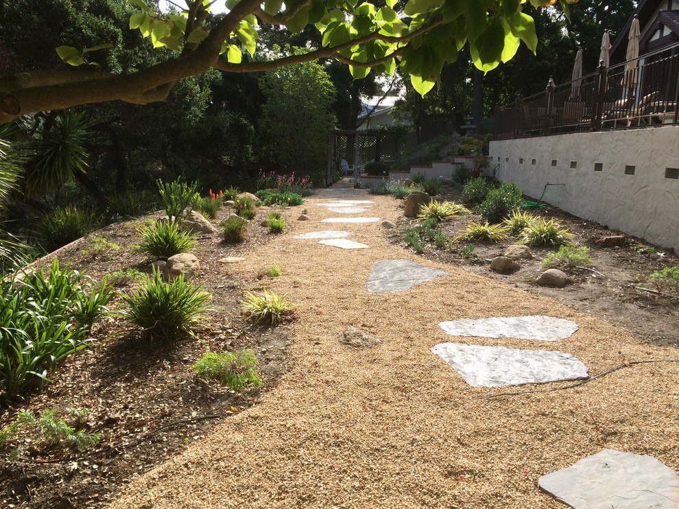 Immagine di un piccolo giardino xeriscape mediterraneo esposto in pieno sole dietro casa con un ingresso o sentiero e pavimentazioni in pietra naturale