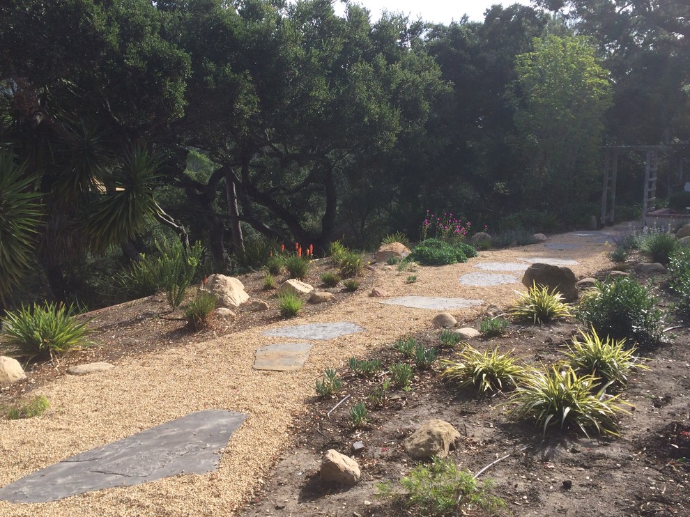 This is an example of a small mediterranean back xeriscape full sun garden in Santa Barbara with a garden path and natural stone paving.