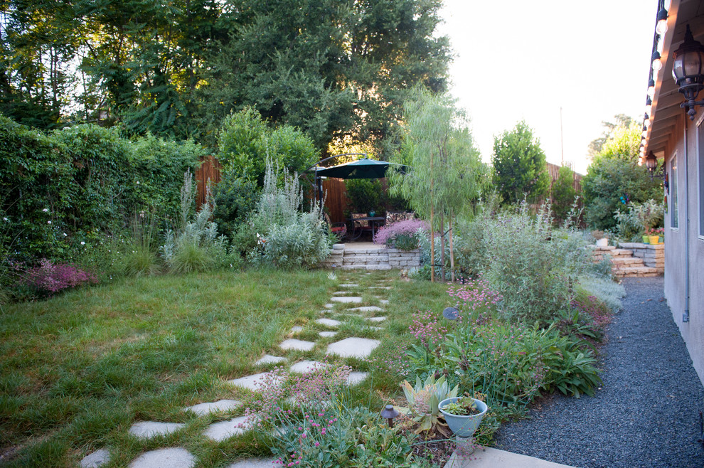 Cette image montre un petit jardin arrière chalet l'été avec une exposition ensoleillée et du gravier.